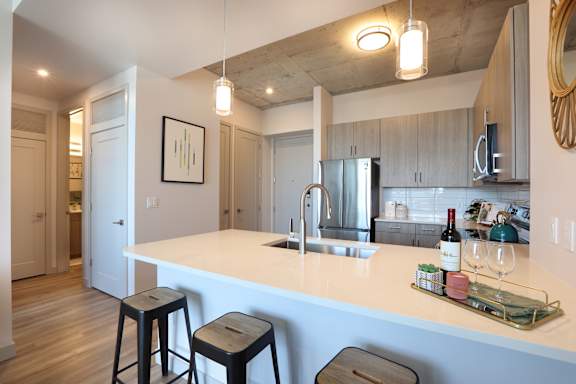 A kitchen with a white counter top and bar stools.