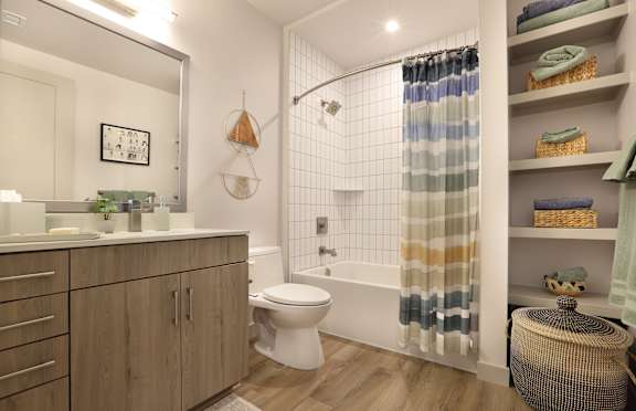 A bathroom with a white toilet, a shower curtain, and a wooden cabinet.