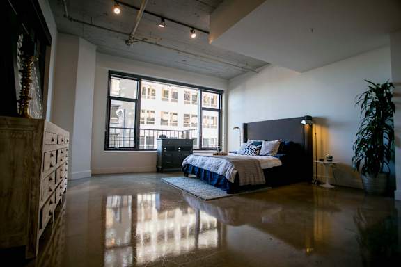 A bedroom with a bed, dresser, and a large window.