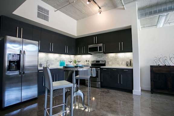 A kitchen with black cabinets and a stainless steel refrigerator.