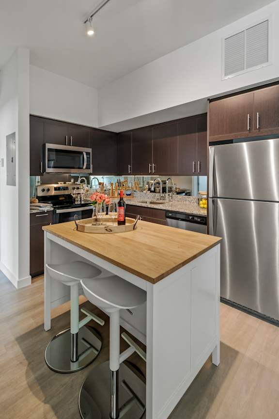 A modern kitchen with a wooden island and stainless steel appliances.