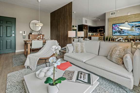 A living room with a white couch and a coffee table with a vase of flowers on it.