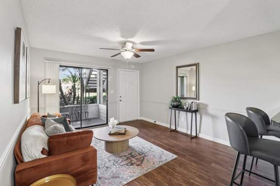 A living room with a brown couch, a coffee table, and a ceiling fan.