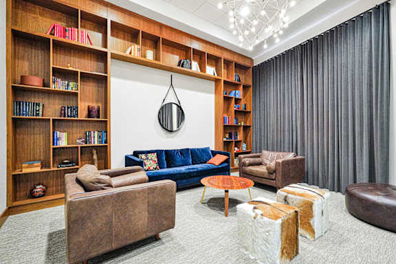 A living room with a blue couch and a wooden bookshelf.