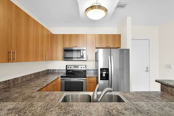 A kitchen with a granite countertop and stainless steel appliances.