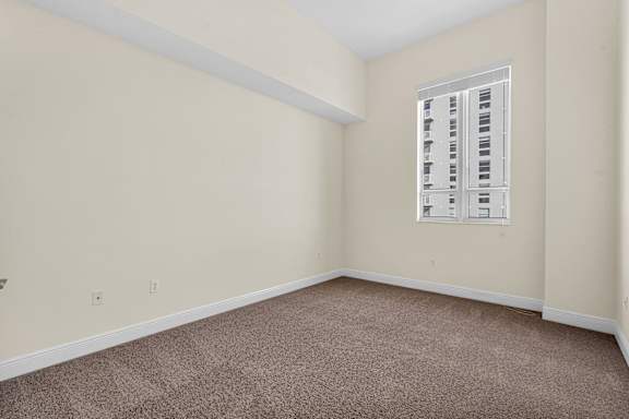 A room with a carpeted floor and a window with blinds.