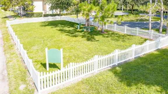 a white picket fence surrounds a yard with a lawn chair