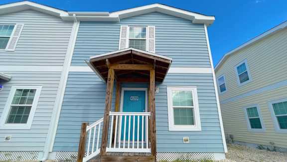 A blue house with a white door and windows.