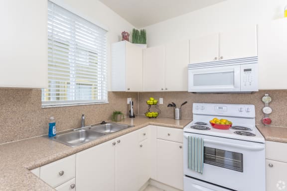 a kitchen with white appliances and granite counter tops and white cabinets