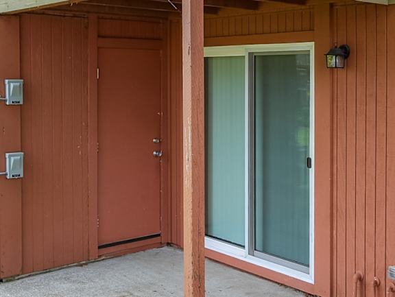 A brown wooden door with a glass window is closed.