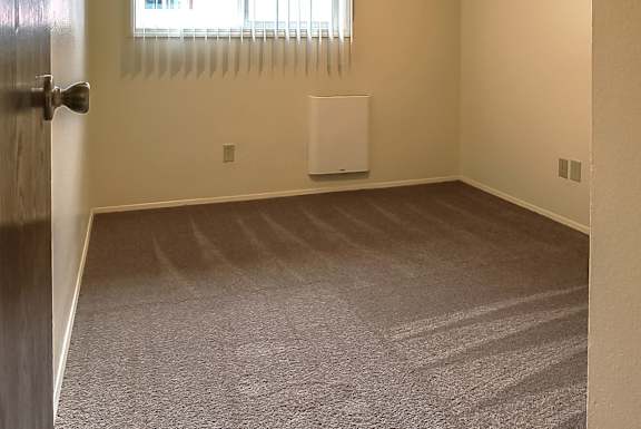 A room with a carpeted floor and a door on the left side.