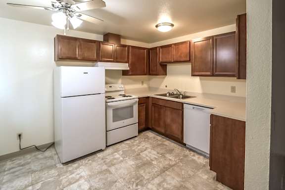 A kitchen with white appliances and brown cabinets.