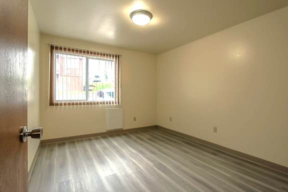 A room with a LVP floor and a window with blinds.
