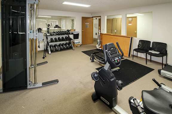 A gym with a variety of equipment including treadmills, weights, and exercise machines.