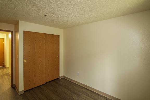 A room with a brown door and wooden floor.