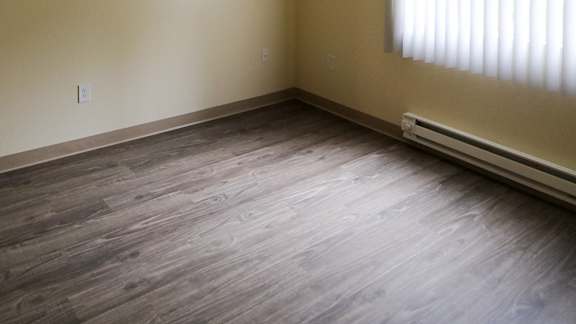 A room with a wooden floor and a window with blinds.