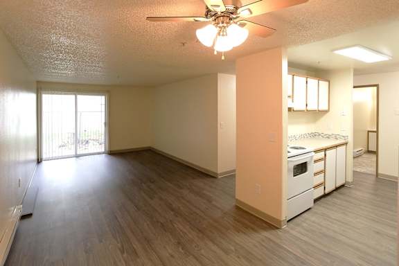 A room with a ceiling fan and wooden flooring.