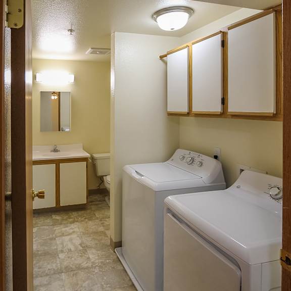 A bathroom with a washer-dryer, sink, and mirror.