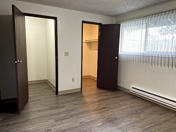 A room with a vinyl plank floor and two open doors.