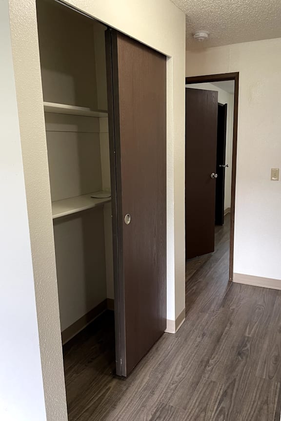 A white wall with a brown door and a white shelf.