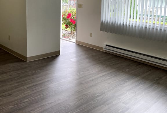 A room with wooden floors and a window with blinds.