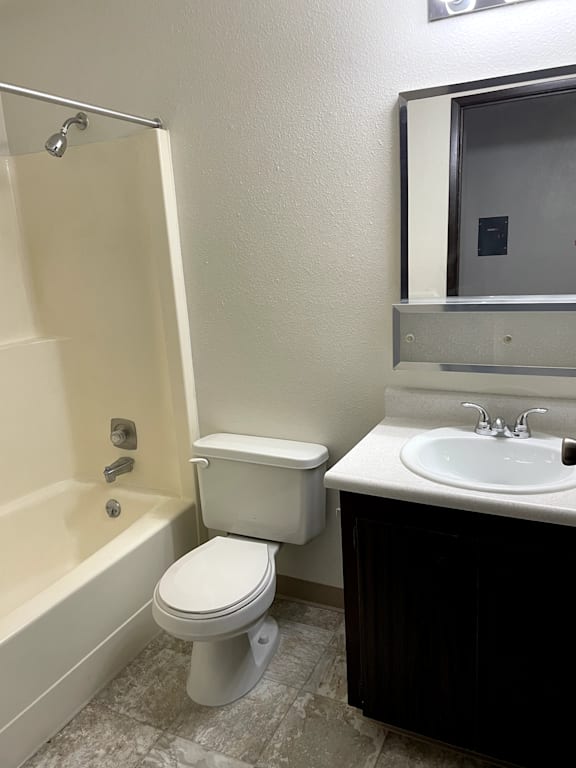 A white toilet sits next to a white bathtub in a bathroom.