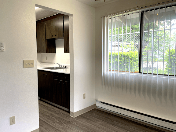 A kitchen with white walls and wooden cabinets.