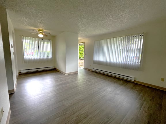 A room with a ceiling fan and two windows with blinds.