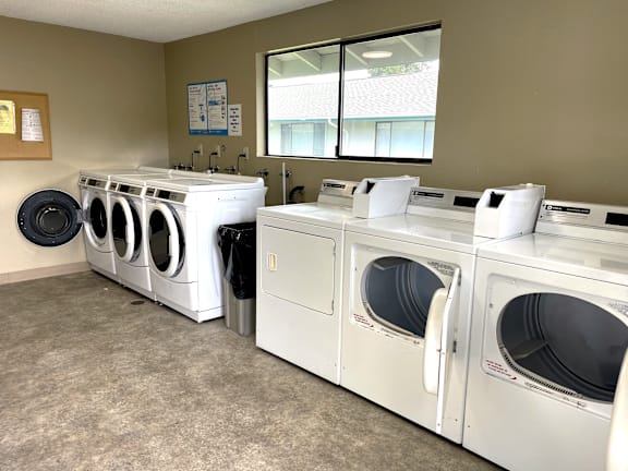 A row of white front load washing machines in a laundromat.