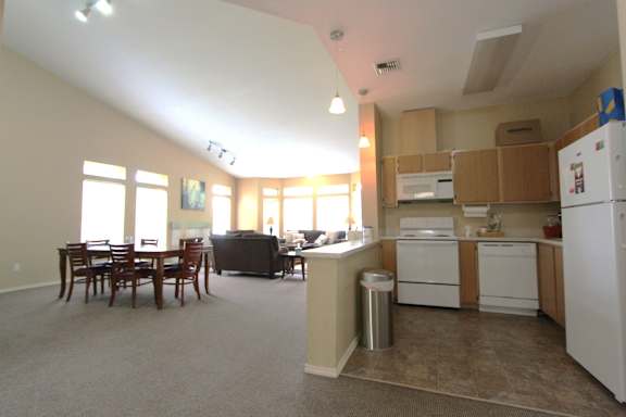 A kitchen with white appliances and a dining table with chairs.