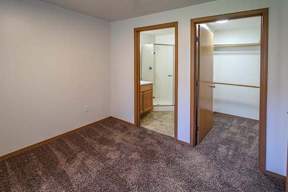 A room with a carpeted floor and a doorway leading to another room.