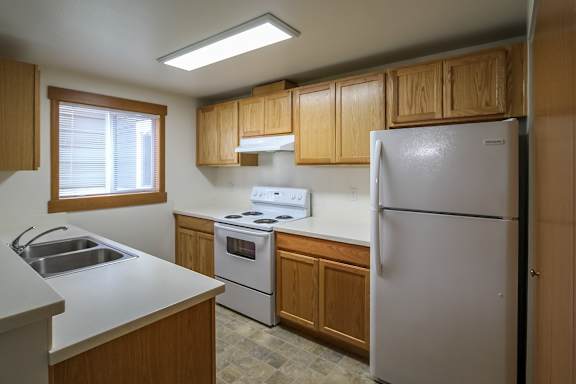 A kitchen with a white refrigerator, sink, and stove.
