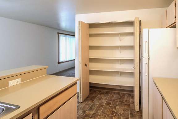A kitchen with a sink, refrigerator, and cabinets.
