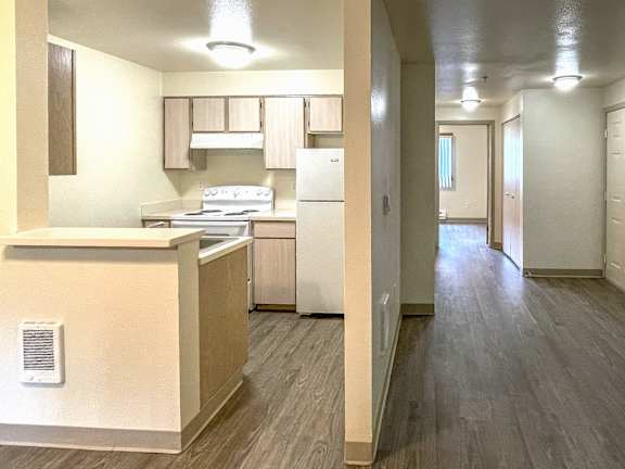 A kitchen with a refrigerator, stove, and cabinets.