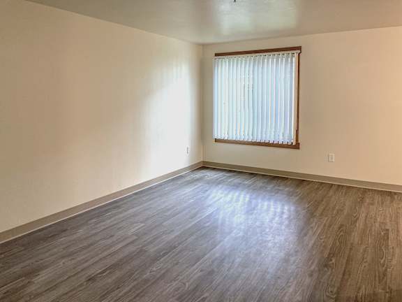 A room with vinyl plank flooring and a window with blinds.