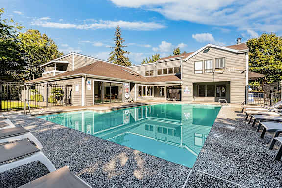 A large swimming pool in front of a building with a sunny day.