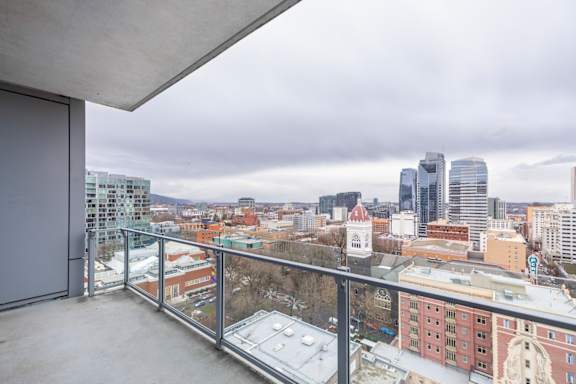 A balcony overlooks a cityscape with buildings and a cloudy sky.