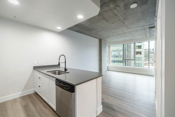 A modern kitchen with a concrete ceiling and a large window.