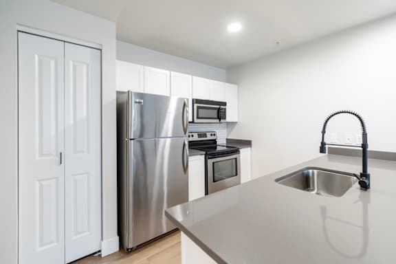A modern kitchen with a stainless steel refrigerator, oven, and microwave.