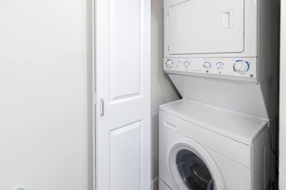 A white washing machine sits next to a white door.