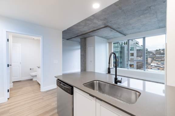 A modern kitchen with a concrete ceiling and stainless steel sink.