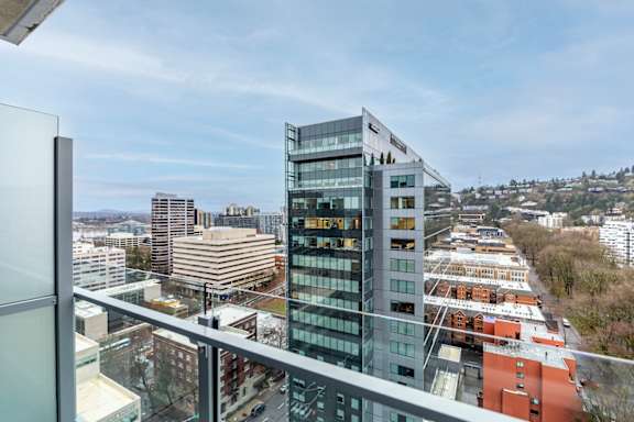 A modern glass building with a balcony overlooking a cityscape.