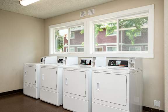 A row of white washing machines in a laundromat.