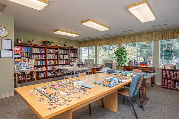 A room with a table, chairs, and a puzzle on the table.