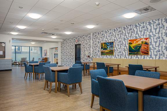 A room with tables and chairs and a wallpapered wall.