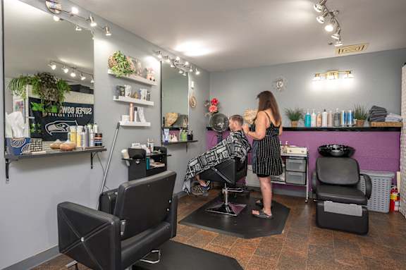 A woman is getting her hair cut by a barber in a salon.