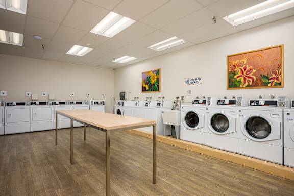 A laundromat with a long table in the middle and washing machines on both sides.