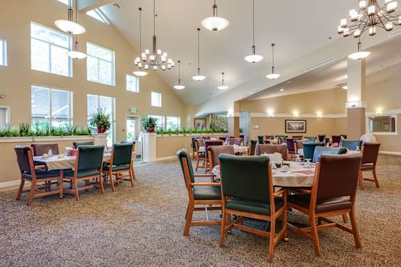 A large room with tables and chairs is well lit with natural light.
