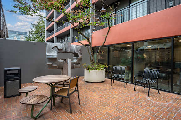 A patio with a table and chairs and a bench outside a building.