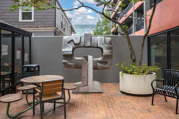 A patio with a table, chairs, and a sculpture.
